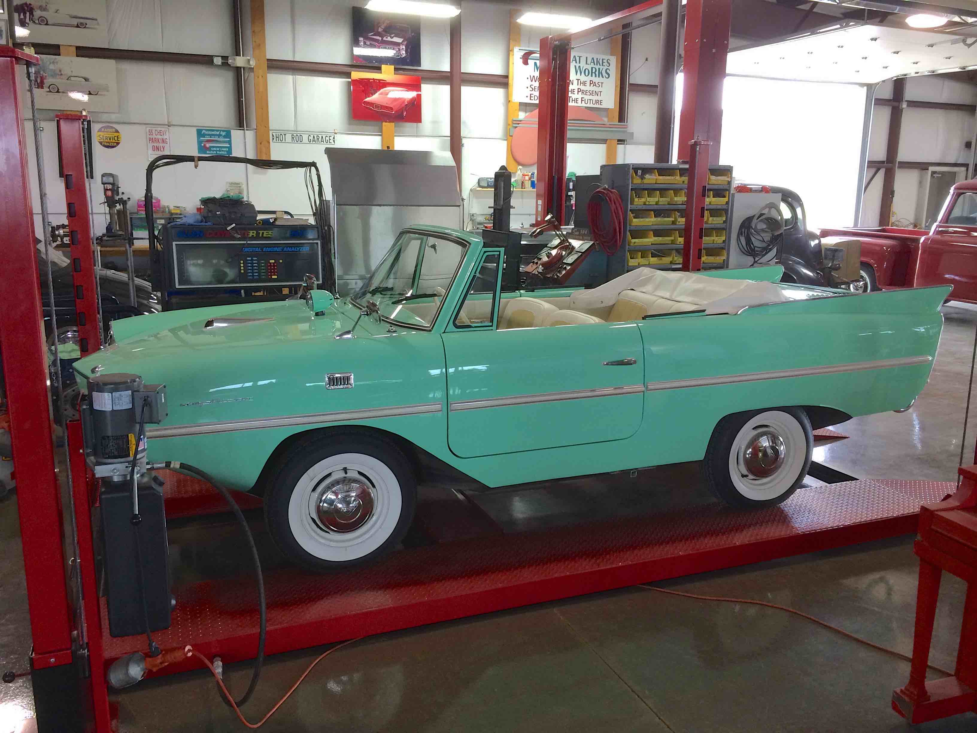 Vintage teal convertible up on a shop lift