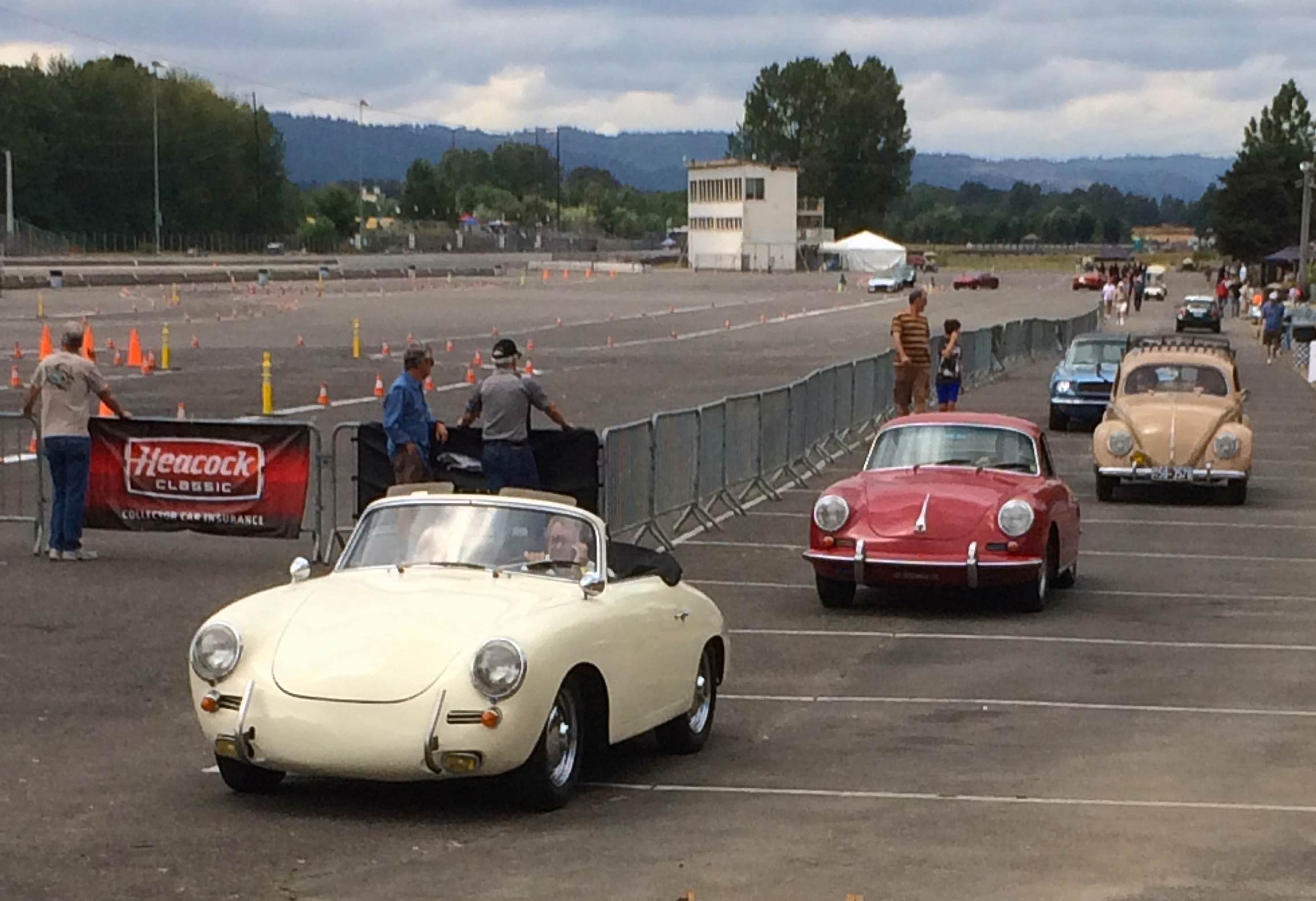 Classic Porsches and VW driving through a car show or tour parking lot